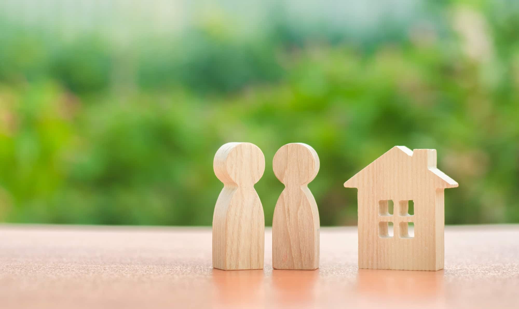 Two wooden figures of people and a house on a nature background